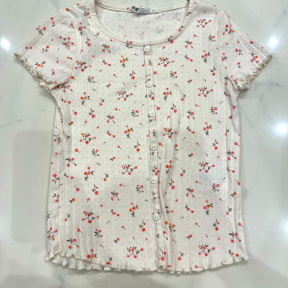 White top with decorative buttons, light ruffles, and red flowers!